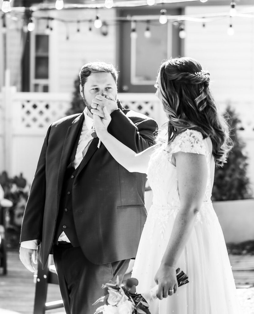 Groom kisses bride's hand at the Vandiver Inn Havre De Grace, black and white wedding photography